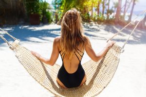 Young beautiful girl in black bathing suit with long blonde hair relaxing in hammock on the tropical beach-img-blog